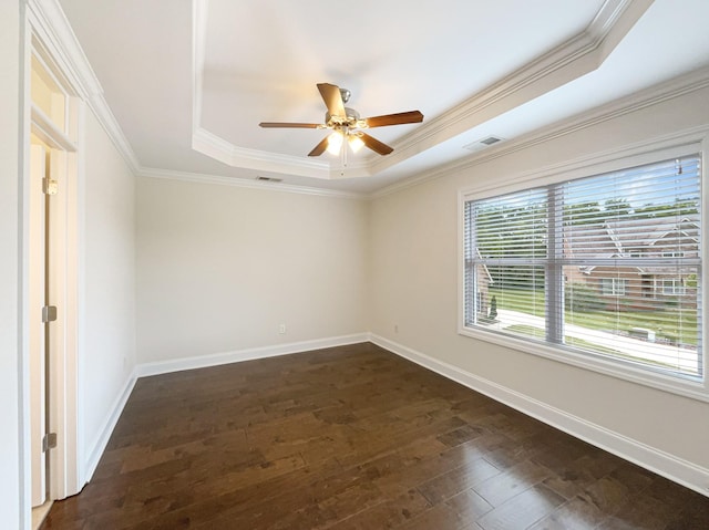 empty room featuring visible vents, ceiling fan, dark wood-style floors, a tray ceiling, and baseboards