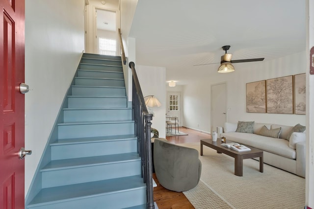 staircase with hardwood / wood-style floors and ceiling fan