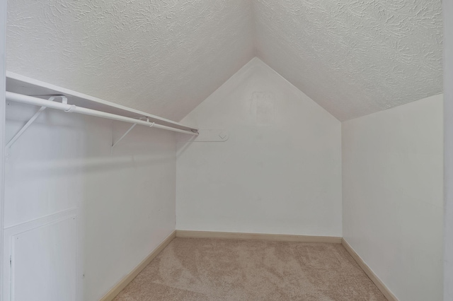 walk in closet featuring light colored carpet and vaulted ceiling