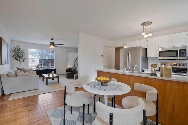 kitchen with backsplash, white cabinets, decorative light fixtures, and appliances with stainless steel finishes