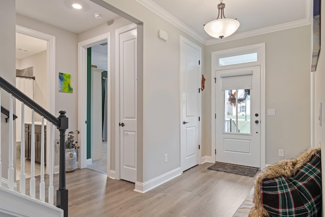 foyer entrance with ornamental molding, a wealth of natural light, and light wood-type flooring