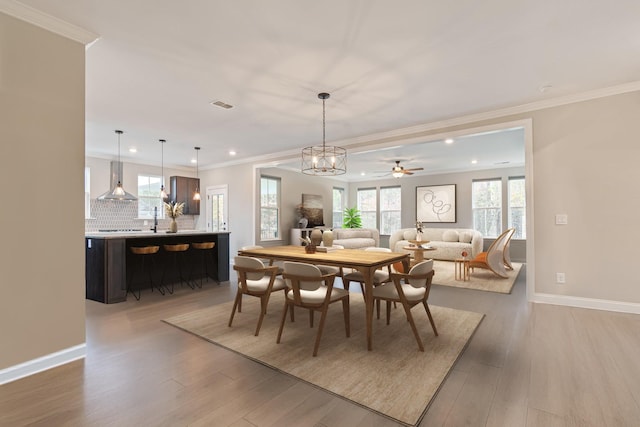 dining space featuring ornamental molding, ceiling fan with notable chandelier, and light hardwood / wood-style floors