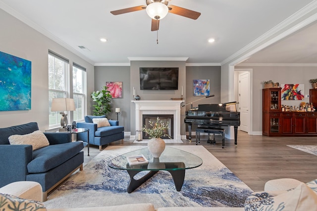 living room featuring hardwood / wood-style flooring, ornamental molding, and ceiling fan