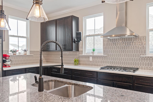 kitchen with stainless steel gas cooktop, sink, crown molding, wall chimney range hood, and backsplash