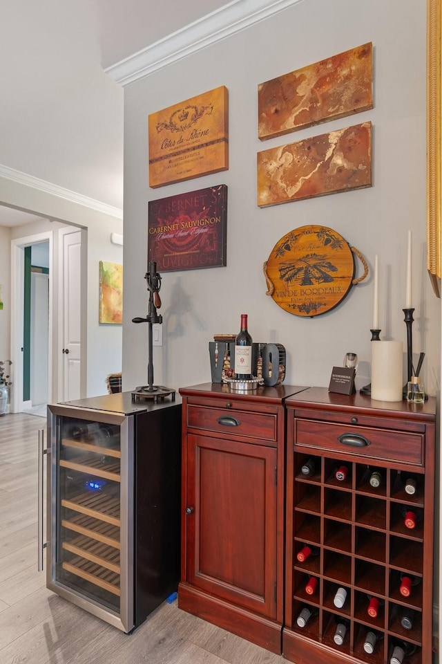 bar featuring crown molding, beverage cooler, and light wood-type flooring