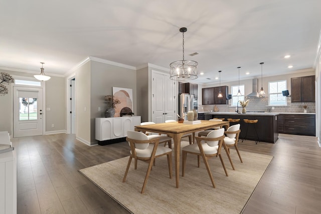 dining area featuring ornamental molding, plenty of natural light, hardwood / wood-style floors, and an inviting chandelier