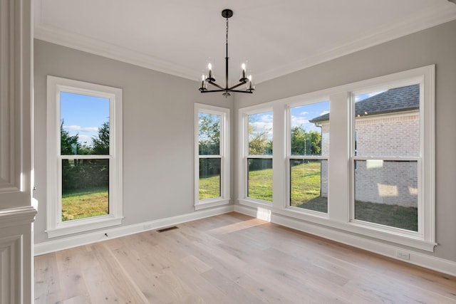 unfurnished dining area featuring crown molding, light hardwood / wood-style floors, and an inviting chandelier