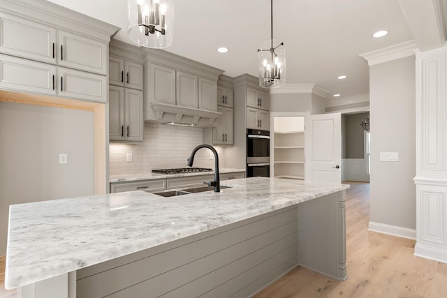 kitchen featuring stainless steel appliances, light stone counters, light hardwood / wood-style floors, decorative light fixtures, and ornamental molding