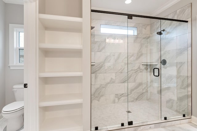 bathroom with built in shelves, toilet, a shower with shower door, and crown molding