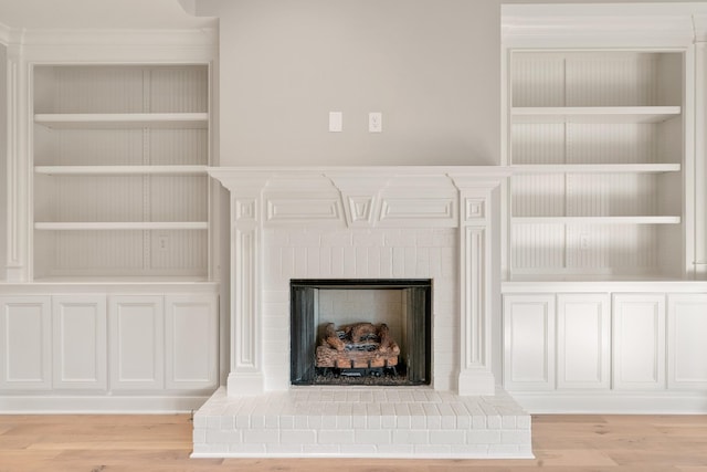 interior details with built in shelves, wood-type flooring, and a fireplace