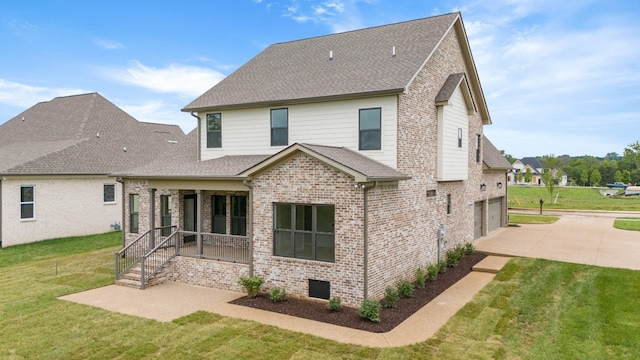 rear view of property featuring covered porch, a garage, and a lawn