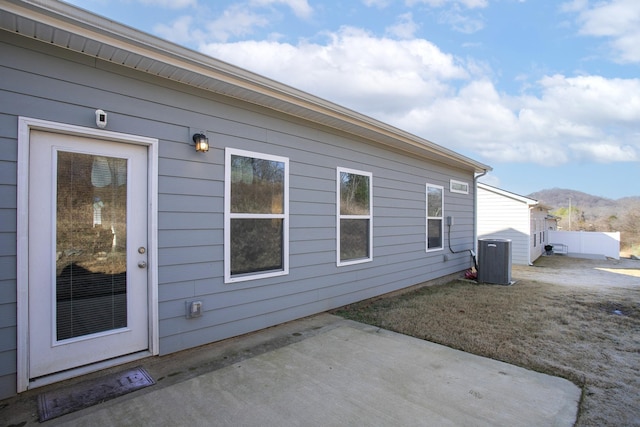 view of side of property featuring a mountain view, a patio area, and central air condition unit