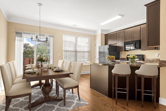 kitchen featuring dark brown cabinetry, black appliances, decorative light fixtures, and ornamental molding