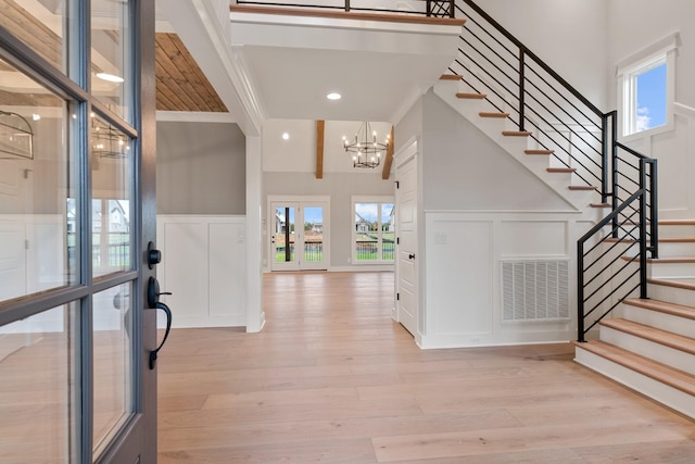 entrance foyer featuring light hardwood / wood-style flooring, beamed ceiling, a chandelier, and ornamental molding