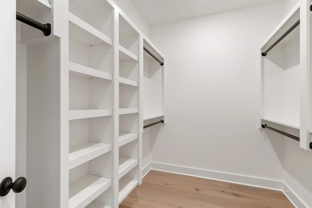 walk in closet with light hardwood / wood-style flooring