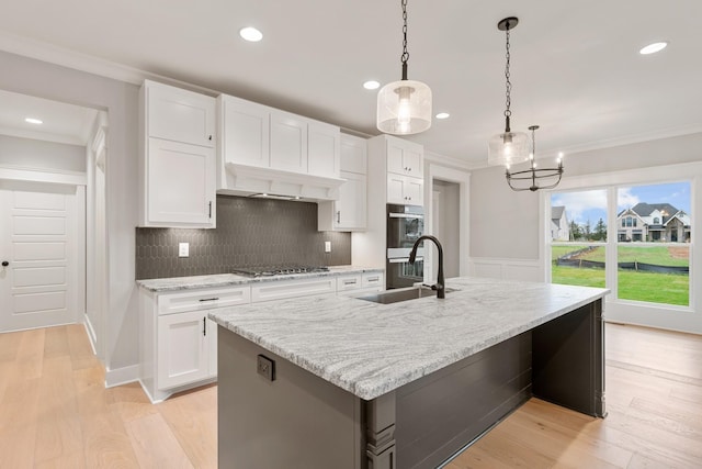 kitchen featuring a center island with sink, white cabinets, and pendant lighting