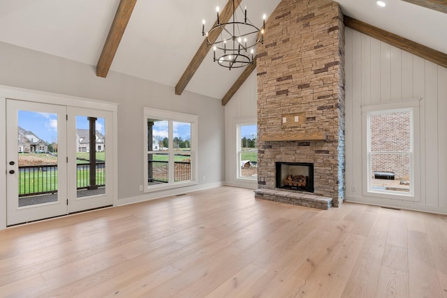 unfurnished living room featuring high vaulted ceiling, an inviting chandelier, a fireplace, beamed ceiling, and light hardwood / wood-style floors