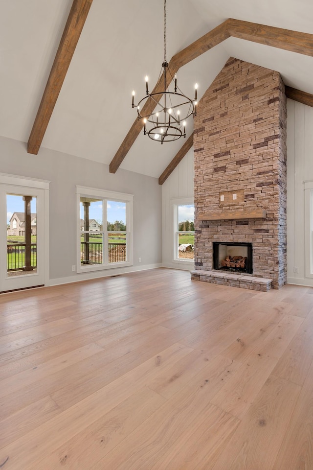 unfurnished living room featuring a fireplace, light wood-type flooring, a chandelier, and high vaulted ceiling