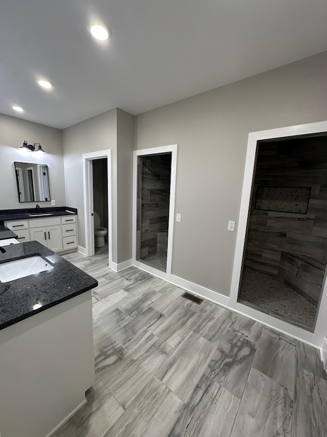 bathroom featuring a tile shower, vanity, and toilet