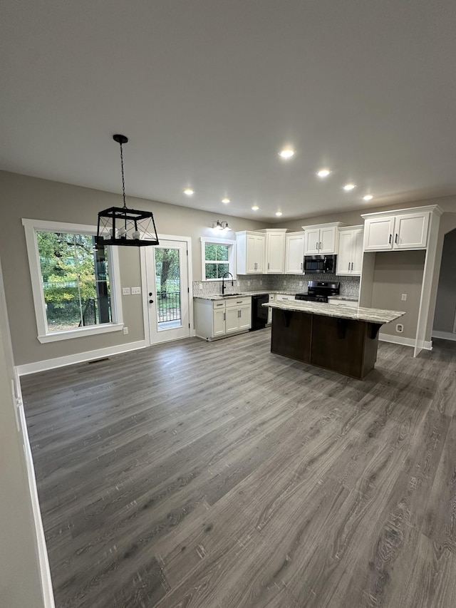 kitchen featuring white cabinets, a kitchen island, black appliances, and hardwood / wood-style flooring