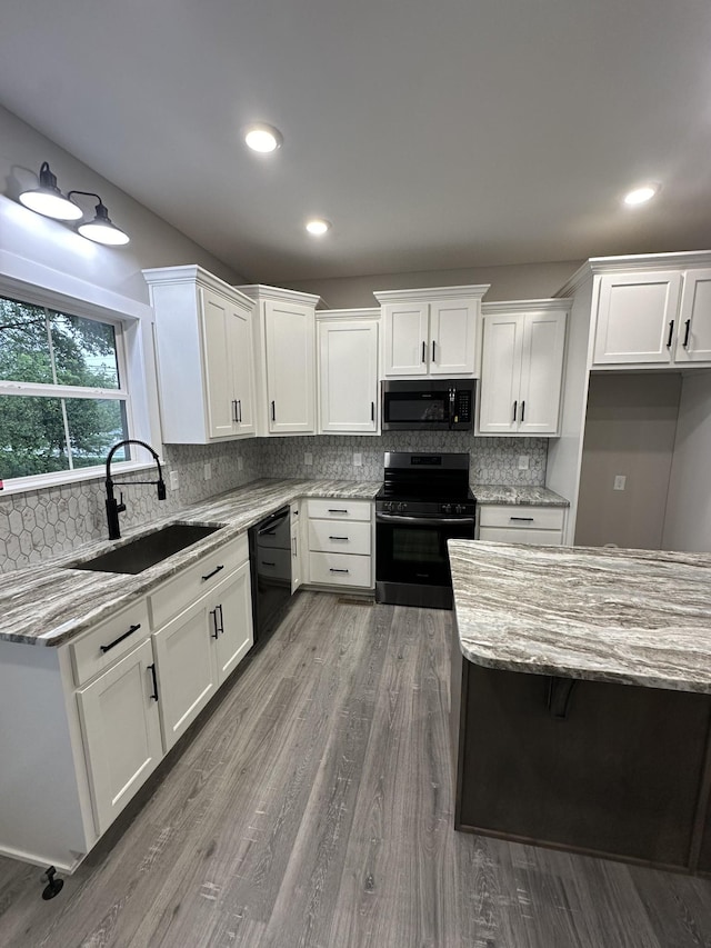 kitchen featuring appliances with stainless steel finishes, light stone counters, sink, hardwood / wood-style flooring, and white cabinets