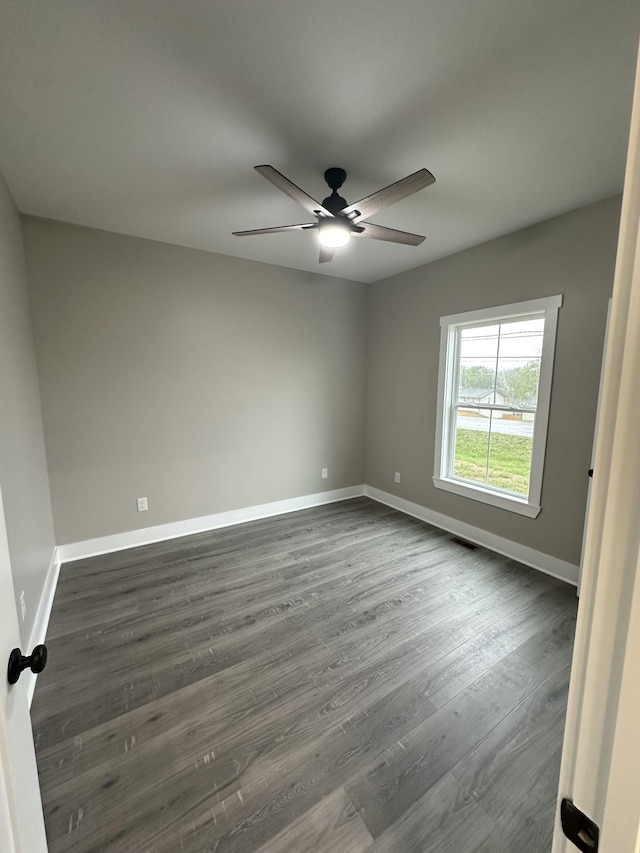 spare room with dark hardwood / wood-style flooring and ceiling fan