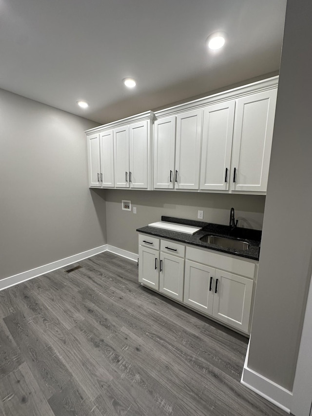 clothes washing area with cabinets, wood-type flooring, sink, and hookup for a washing machine