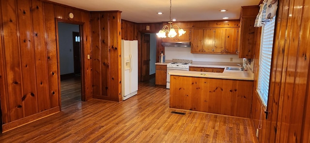 kitchen with sink, a notable chandelier, light hardwood / wood-style floors, decorative light fixtures, and white appliances