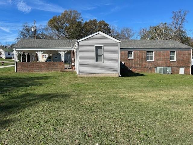 back of property featuring a lawn and central AC