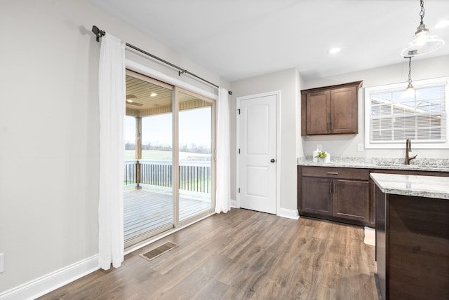 kitchen featuring hardwood / wood-style floors, light stone countertops, sink, and a healthy amount of sunlight