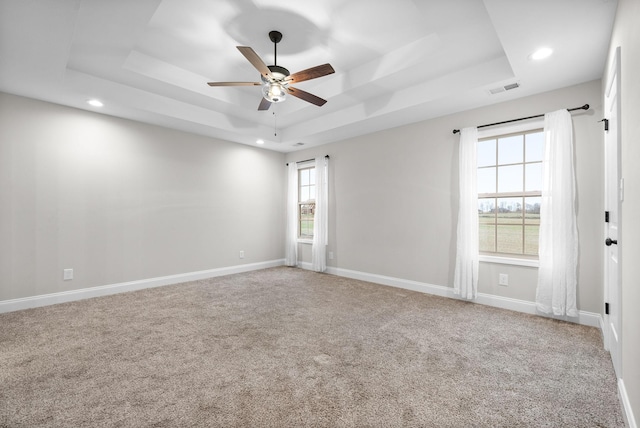 spare room featuring carpet flooring, plenty of natural light, ceiling fan, and a raised ceiling