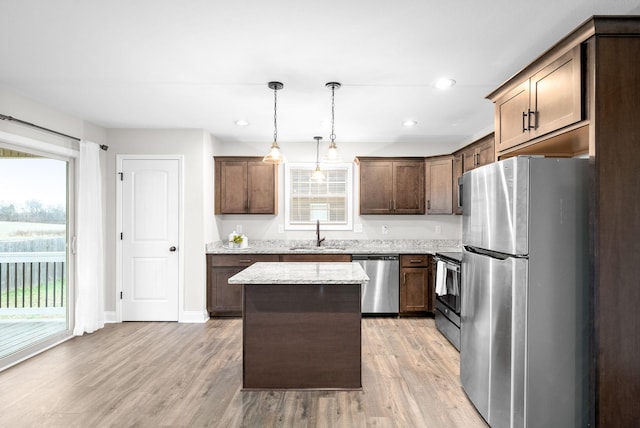 kitchen featuring pendant lighting, sink, light hardwood / wood-style floors, appliances with stainless steel finishes, and a kitchen island