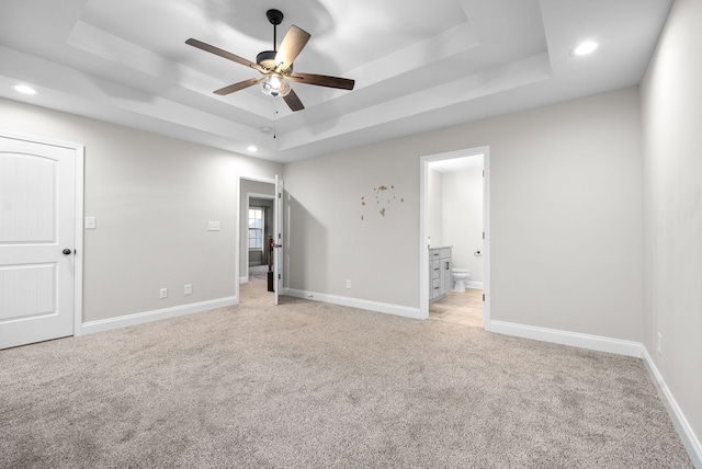 spare room with light colored carpet, a raised ceiling, and ceiling fan