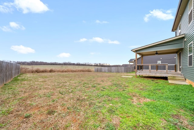 view of yard with a rural view, a deck, and ceiling fan