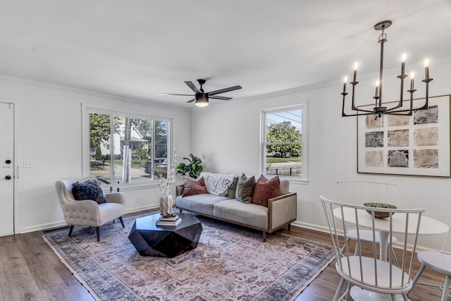 living room featuring hardwood / wood-style floors, ceiling fan with notable chandelier, ornamental molding, and a wealth of natural light