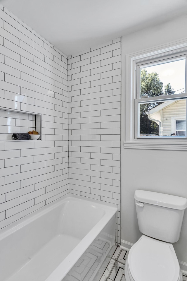 bathroom featuring tile patterned floors, tiled shower / bath combo, and toilet