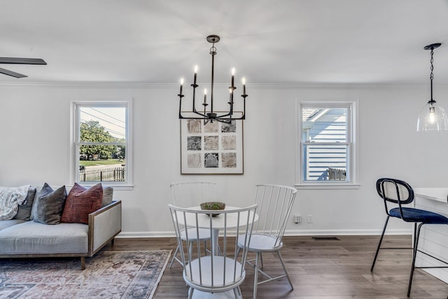 dining area with crown molding, dark wood-type flooring, and ceiling fan with notable chandelier