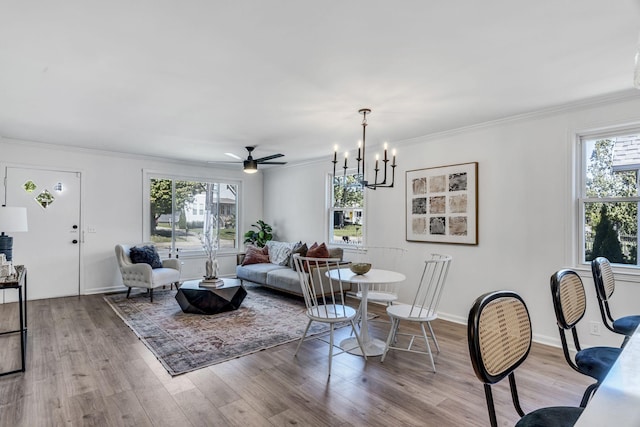 living room featuring a wealth of natural light, light hardwood / wood-style flooring, ceiling fan with notable chandelier, and ornamental molding