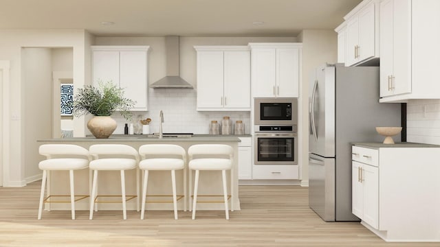 kitchen with white cabinets, appliances with stainless steel finishes, tasteful backsplash, and wall chimney range hood