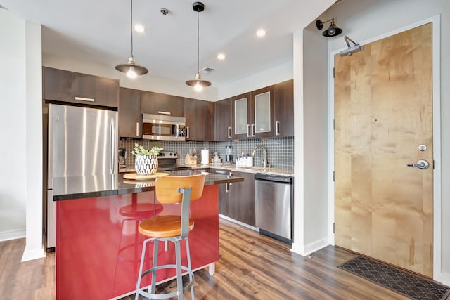 kitchen featuring a center island, decorative light fixtures, appliances with stainless steel finishes, dark brown cabinets, and a breakfast bar area