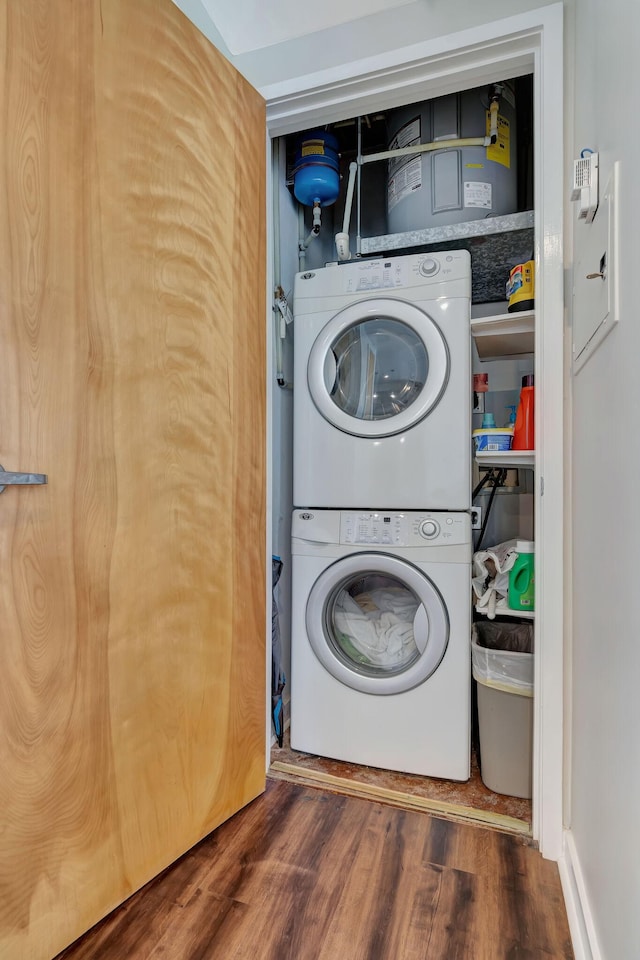 washroom featuring stacked washer and dryer and dark wood-type flooring