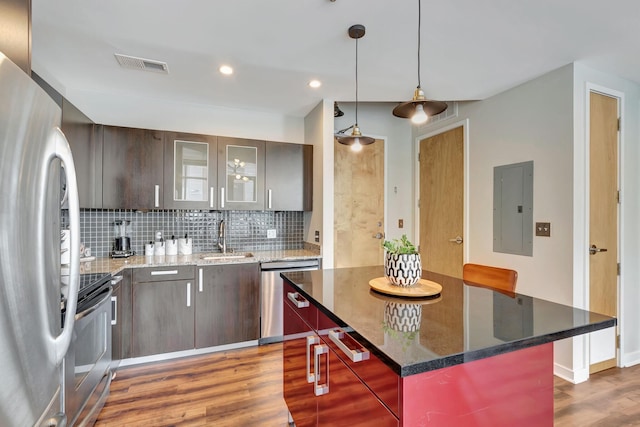 kitchen with appliances with stainless steel finishes, backsplash, dark brown cabinetry, sink, and electric panel