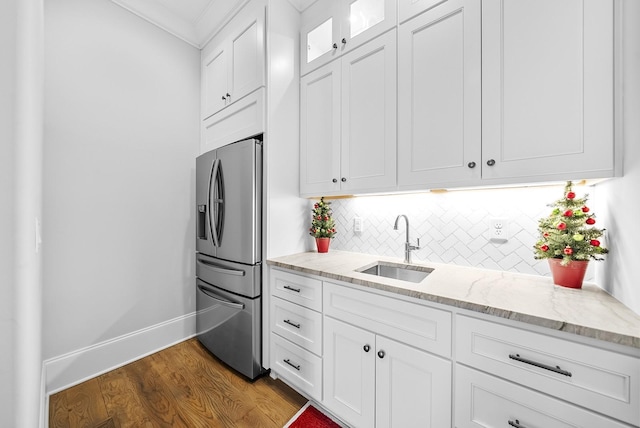 kitchen with backsplash, white cabinets, sink, stainless steel fridge, and light stone counters