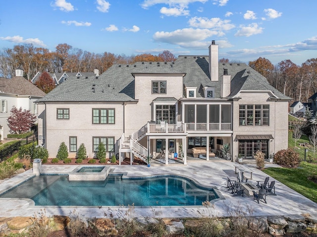 rear view of house featuring a swimming pool with hot tub, a patio area, and a sunroom