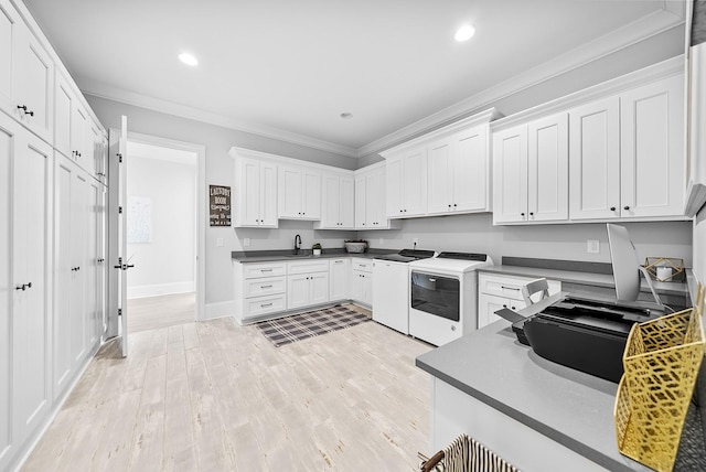 kitchen featuring white cabinets, sink, crown molding, washer and dryer, and light wood-type flooring