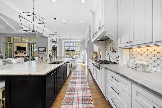 kitchen featuring pendant lighting, a spacious island, sink, a fireplace, and tasteful backsplash