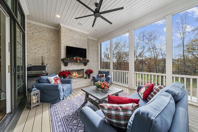 sunroom with ceiling fan, wooden ceiling, a fireplace, and a wealth of natural light