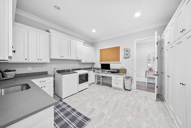 kitchen with washing machine and clothes dryer, white cabinetry, sink, and crown molding