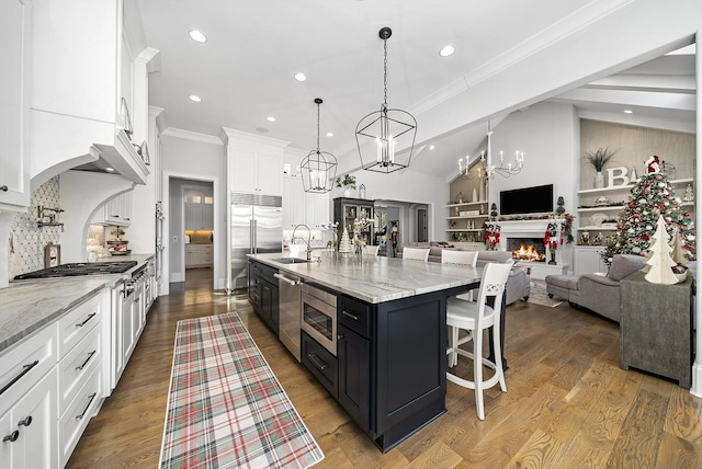 kitchen featuring white cabinetry, built in features, a spacious island, decorative light fixtures, and decorative backsplash