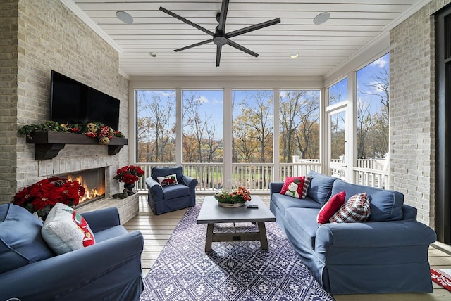 sunroom featuring a stone fireplace, ceiling fan, and wooden ceiling